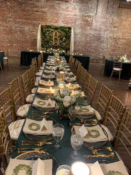 Greenery, tablecloths, napkins, utensils, glasses, and name cards all by Delta Party.